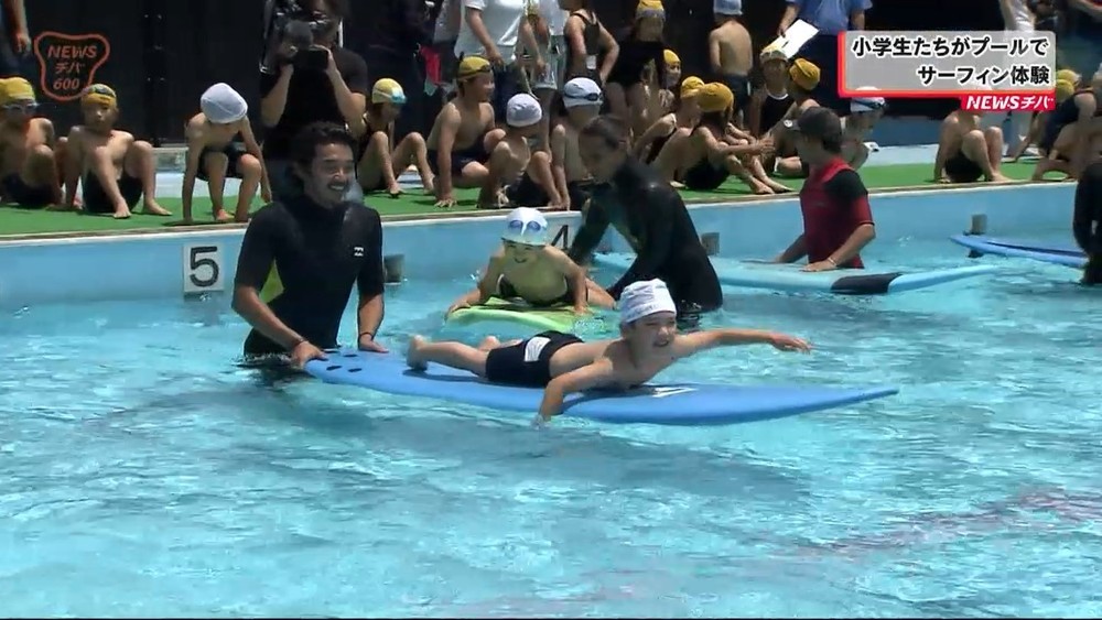 小学生がプールでサーフィン体験
